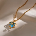 Nahaufnahme der goldenen Schleife-Halskette mit blauem Herzanhänger auf Stoff - Blau