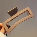 Detailed view of large brown matte resin hair claw clip held by hand against grey wall - 13cm / Dark Coffee