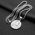 Macro shot of silver Virgo Pray pendant on ball chain against black leather background - Virgin Mary Portrait - Steel Color - 60cm Box Chain