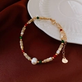 Détail d'un bracelet de perles vintage français avec pendentif cœur sur soie rouge - Bracelet Vintage Français en Acier Inoxydable avec Perles Irrégulières et de Couleur