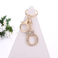 Golden letter O keychain with crystal rhinestones and crown detail on a white stand - Letter O / Gold