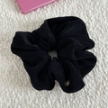 Detail of a soft black towel cloth scrunchie with a round handmade metal tag on white fabric - Scrunchie / Black