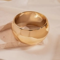 Close-up of a wide polished gold metal cuff bracelet on a stone pedestal - Gold Round Large