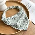 Detail view of a white floral chiffon head kerchief with green daisy pattern on a wooden tray - Green