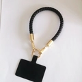 Nahaufnahme der schwarzen geflochtenen Handykette mit goldener Metallschnalle und Lasche - Goldschnalle + Schwarzes Band + Schwarzes Pad