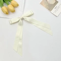 Close-up of cream double-layered satin bow hair clip with ribbons on aesthetic background - Beige