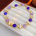 Close-up of gold bracelet with purple gemstones and pearls in a beige jewelry box - Gold Necklace