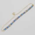 Detail eines handgefertigten Tila-Perlenarmbands mit blauen und goldenen Perlen und Kordel - Blau Gold Grau