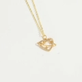Detailweergave van een gouden hartjesketting met witte zirkoon op een witte achtergrond - Hart Saturnus Ring Hanger / Hart XL3374-4