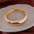 Vista macro dettagliata di un bracciale rigido dorato lucido con chiusura a cerniera - Oro Lucido