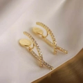 Elegant gold X-shaped crisscross earrings with micro-paved cubic zirconia on satin background - Gold Crossed Rhinestone Earrings
