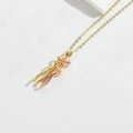 Gros plan d'un collier pendentif étreinte bicolore or et or rose sur cuir blanc élégant - Étreinte Or & Or Rose