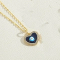 Makro-Detail der goldenen Herz-Halskette mit blauem Evil-Eye-Anhänger und weißen Zirkonia - Herz Böser Blick Stil (XL3159-1)