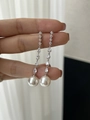 Long tassel pearl drop earrings with silver cubic zirconia held by hand against a wall - Classic White