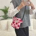 Pink plush crossbody bag with red hearts shown being worn by a model in a lifestyle setting - Pink Hearts