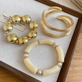 Gros plan d'un ensemble de bracelets en perles dorées et acrylique sur plateau - 51# Jonc - Kaki / Ensemble trois pièces / Or