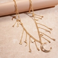Detalle de dijes de luna y estrella dorados en una cadena de cintura con perlas sintéticas - Dorado