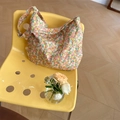 Lifestyle-Detail einer großen Stofftasche mit Blumenmuster auf einem gelben Stuhl - Cord Orange Blumen