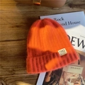 Detail of orange knitted beanie with 1982 California patch on a wooden background - M / Orange Red
