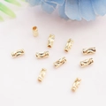 14K vergulde holle buiskralen voor DIY sieraden maken op witte getextureerde stof - Gesneden Kraal / 14K Goud