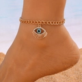 Detailed view of gold evil eye anklet with blue crystal on a model foot at the beach - KC Gold Color Layered Evil Eye Chain Style (11411)