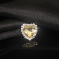 Macro shot of heart-shaped yellow crystal with white rhinestone halo on black silk - Champagne
