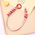 Detail of red and white braided PU leather phone strap with metal rings on a tray - Hand Chain / Red + White