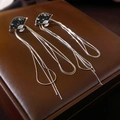 Detailed close-up of fan-shaped tassel earrings with black enamel on brown leather - Silver Needle - Black Fan Tassel Earrings