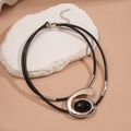 Dettaglio del ciondolo a spirale argento con gemma nera su doppio cordino intrecciato - Collana / Argento