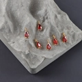 Macro detail of six red pear-shaped zircon pendants with 18k gold plated prong settings - Red Water Drop Style (M108902)