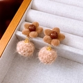 Dettaglio macro di orecchini a fiore marroni con pendenti a sfera in lana beige in scatola - Stile Caffè (Ago d'argento)