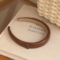 Elegant brown faux leather headband with small metal buckle on a minimalist book background - Caramel color
