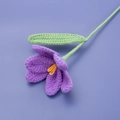 Close-up of handmade purple knitted tulip flower with yellow stamen and green leaf - Finished Open Tulip Bouquet (purple)
