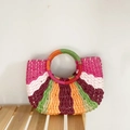 Close-up of vibrant multicolored woven texture and circular handle on the straw bag - Rose Red