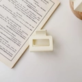 Detailed close-up of a matte cream square hair claw clip on a minimalist book background - Matte Milk White