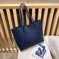Deep blue lychee pattern tote bag with tassel pendant and magnetic clasp on bed - Blue