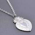 Détail macro du pendentif coeur sacré en argent avec rayons et reliefs floraux - Set de colliers / Couleur Acier