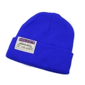 Close-up detail of Klein blue knitted beanie with airline boarding pass style patch label - Blue