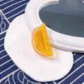 Detailed close-up of realistic resin orange slice hair clip on a white ceramic plate - Half Orange Slice