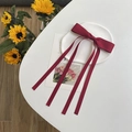 Close-up of a red double-layered ribbon bow hair clip with elegant long streamers - Burgundy