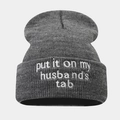 Detailed view of dark grey knit beanie featuring white letter embroidery texture - Dark Gray