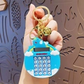Blue unicorn calculator keychain with bell and golden ring in hand close-up - Unicorn Computer - Blue