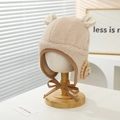 Detail van pluche kindermuts met 3D-oren en leeuwenpatch op een houten standaard - 2-6 Jaar / Beige