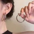 Pendientes de aro plateados pulidos con diseño minimalista mostrados puestos y sujetos - Estilo de Aro Pulido Grande Plateado (MY33111)