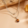 Gros plan d'un collier double rang argenté avec perle ronde et pendentif œil de tigre - Oeil de Chat Rond Couleur Acier (K803)