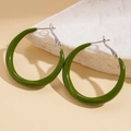 Detail of green circular hoop earrings on white stone props with silver pins - Hoop Earrings-Green-Silver Buckle