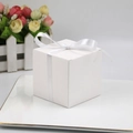Boîte cadeau carrée blanche pour bonbons avec ruban élégant sur un plateau décoratif - Blanc