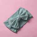 Detail view of mint green cable-knit baby headband with a large bow on pink background - Blue Gray
