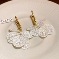 Macro detail of gold earrings with pearl-white textured flower petal tassels on ceramic - Gold-White (Style 2)