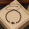 Detail of beaded bracelet with black natural stones and gold beads on a jewelry box - Black